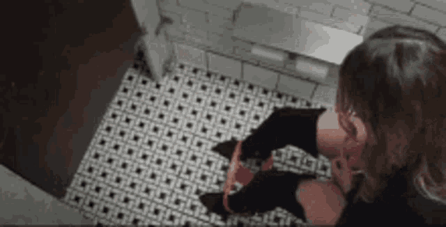 a woman is sitting on a toilet with a red ribbon around her waist .