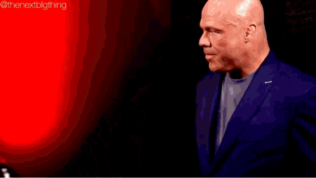 a bald man and a blonde woman are looking at each other in a dark room .
