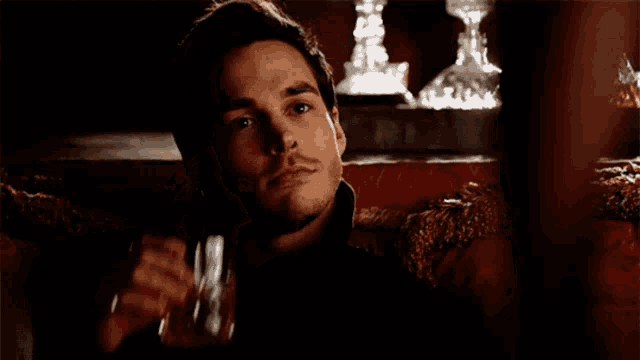 a man is drinking from a glass in a dark room
