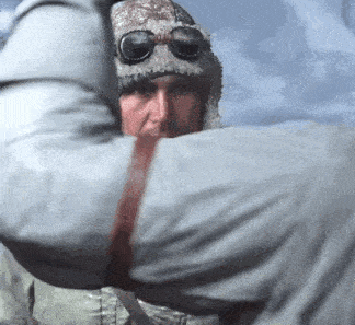 a man wearing a hat and goggles is holding another man 's hand