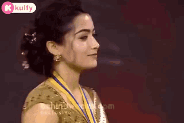 a woman wearing a gold medal around her neck is sticking her tongue out .