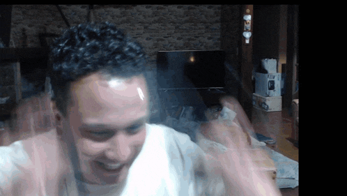 a man with a white shirt on is smiling in front of a tv