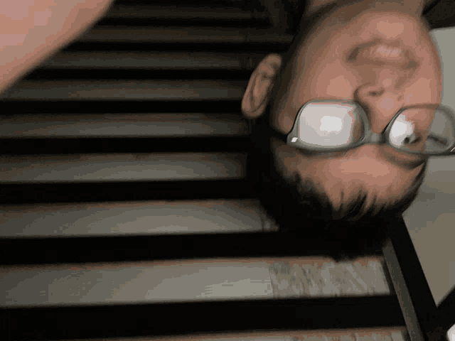 a close up of a person wearing glasses on a staircase
