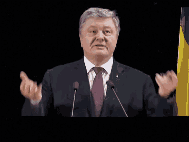 a man in a suit and tie is speaking into microphones