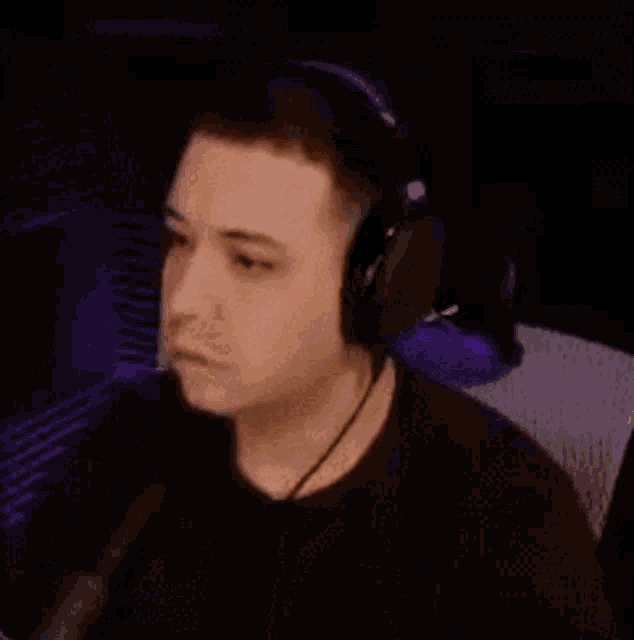 a man wearing headphones is sitting in front of a microphone and making a funny face .
