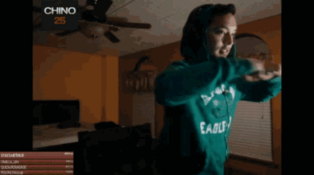 a woman wearing a green eagles sweatshirt is playing a video game