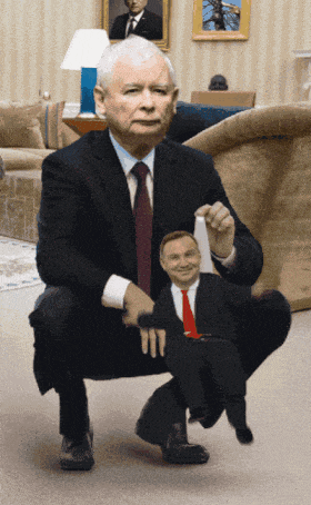 a man in a suit and tie is squatting down holding a puppet of another man