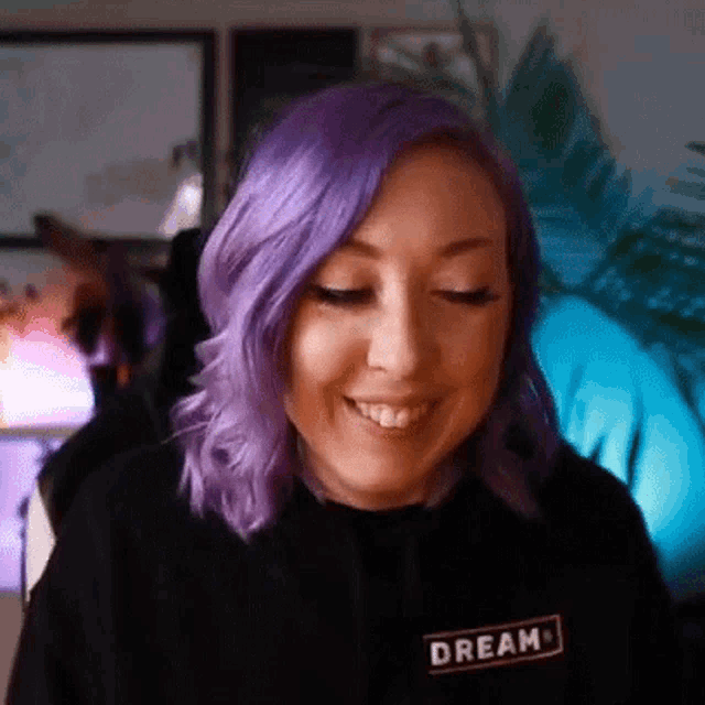 a woman with purple hair is wearing a black hoodie that says dream .