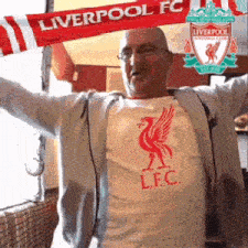a man wearing a liverpool fc shirt holds a scarf