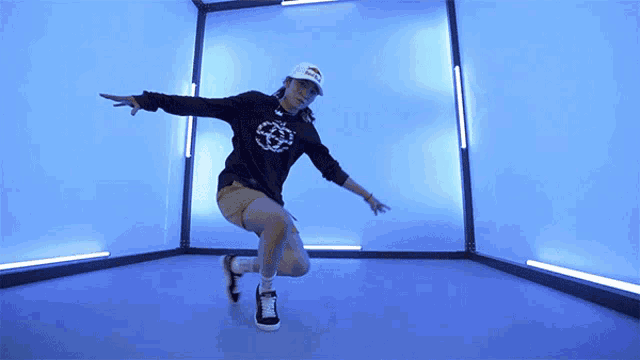 a woman is dancing in a room with blue lights
