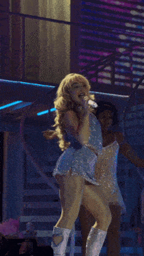 a woman singing into a microphone on a stage