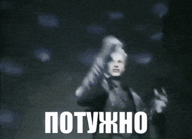 a man in a trench coat is dancing in a dark room with the words " потужно " written above him .