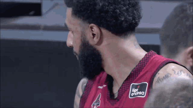 a man with a beard is wearing a red and black jersey that says liga espanola