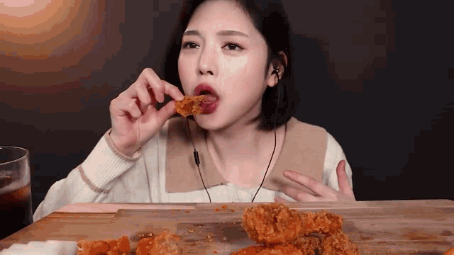 a woman is eating a piece of fried chicken while wearing headphones