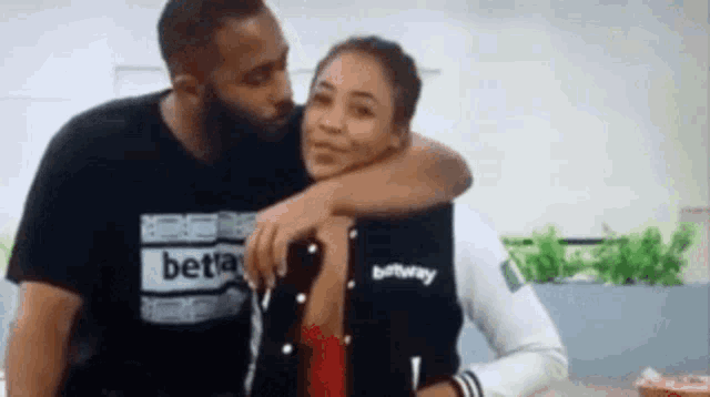 a man is kissing a woman on the cheek while they are hugging each other .