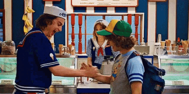 a man in a sailor hat is shaking hands with a boy in a green hat .