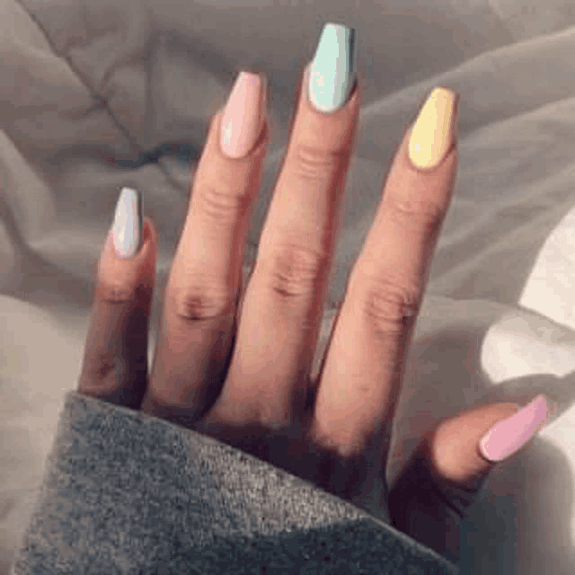 a close up of a person 's hand with colorful nails on a bed .