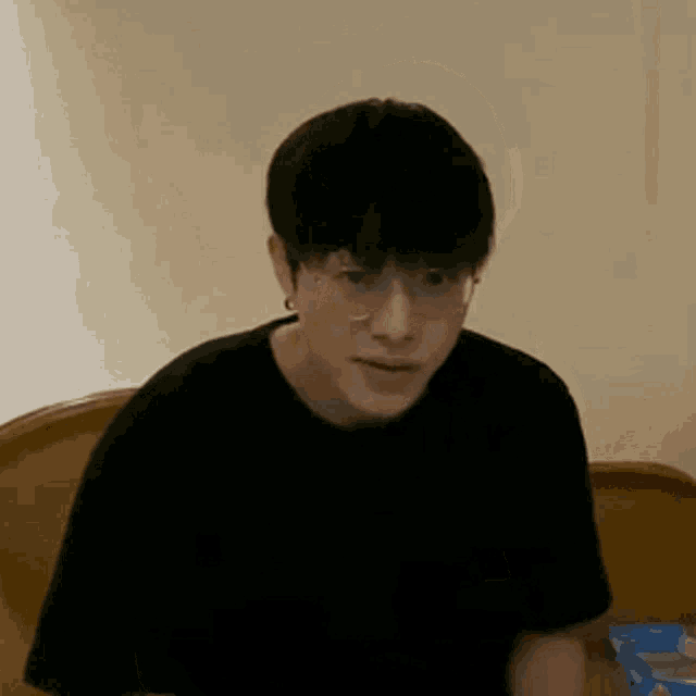 a young man wearing glasses is sitting on a bed and making a funny face .
