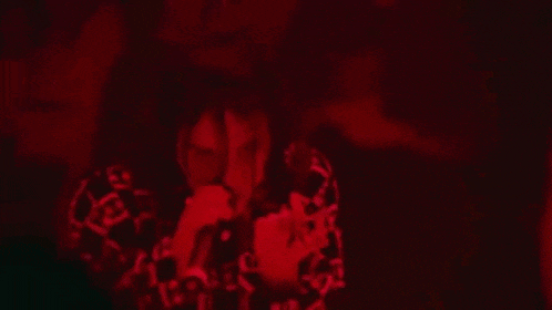a man is singing into a microphone in a dark room with red lights .