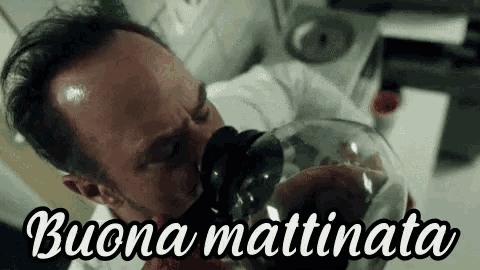 a man is drinking a glass of coffee from a coffee pot .