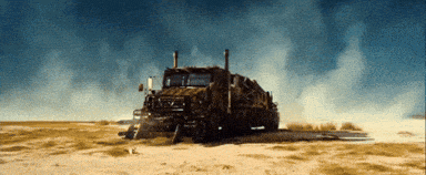 a truck is driving through a desert with smoke coming out of the exhaust pipes