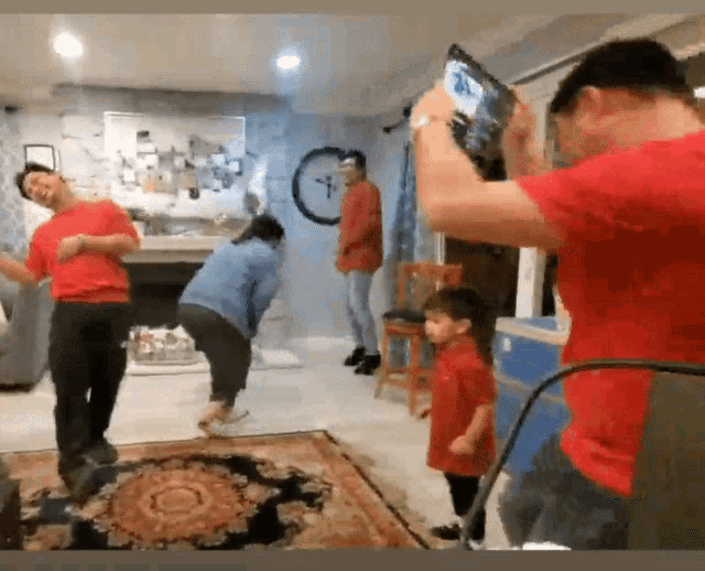 a man is taking a picture of a family dancing in a living room .