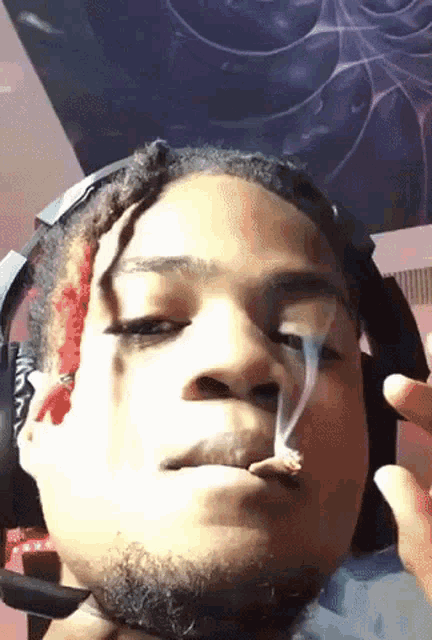 a young man wearing headphones is smoking a cigarette .