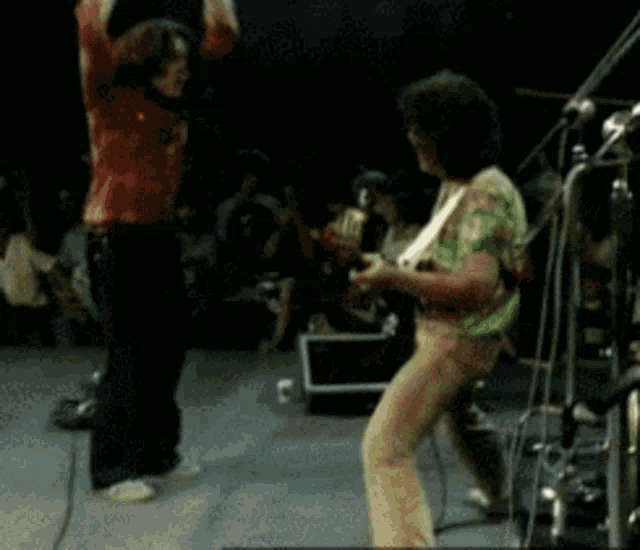 a man in a green shirt is playing a guitar