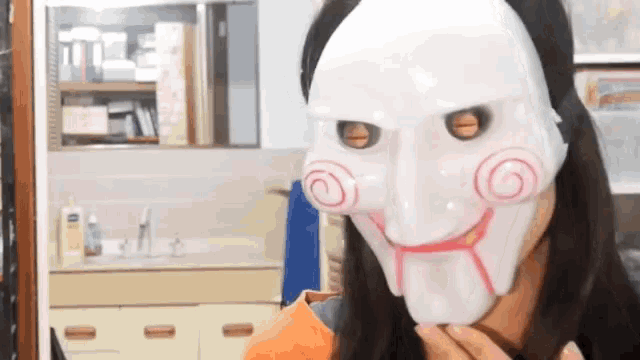a woman wearing a white puppet mask with a smile on her face