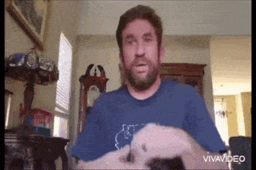 a man with a beard is sitting in a living room with a lamp and a clock .