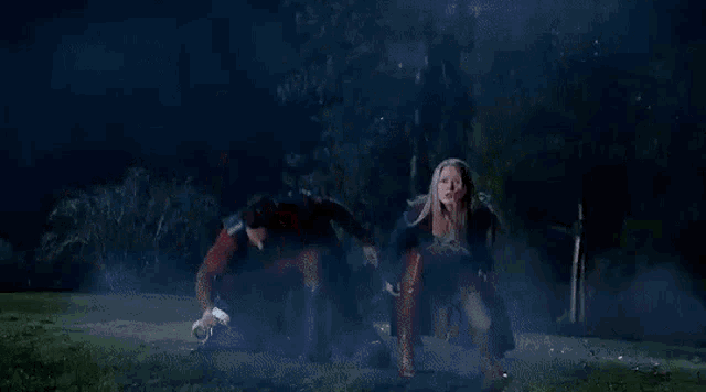 a man and a woman are kneeling on the grass in a field at night .