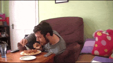 a man sitting in a chair eating a plate of spaghetti and meatballs