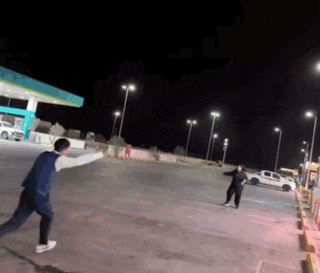 a man throws a frisbee at a woman in a parking lot at night