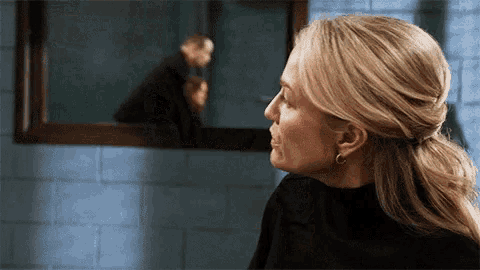 a woman is looking at her reflection in the mirror