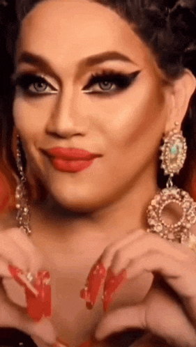a woman with long red nails is making a heart with her hands