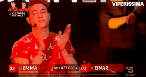 a man in a red shirt is applauding in front of a screen that says viperissima on it