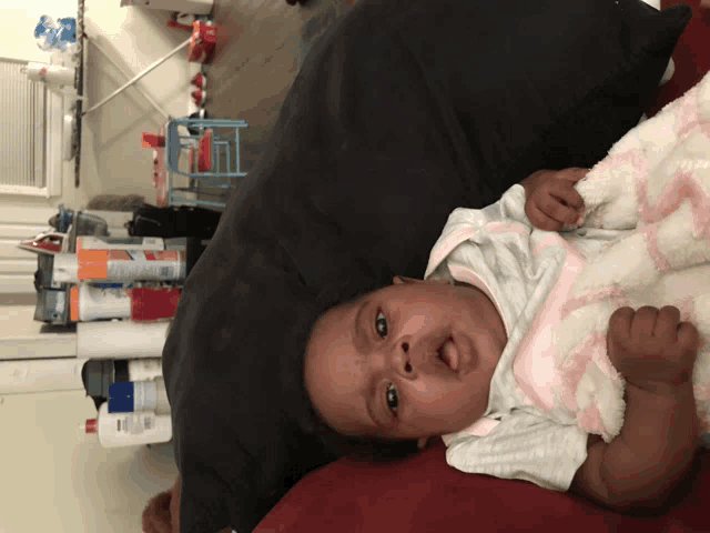 a baby is laying on a bed with a blanket and a can of clorox spray in the background