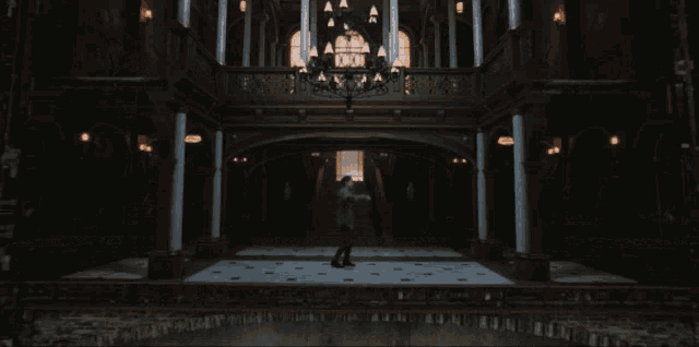 a man in a suit is walking down a staircase in a dark room