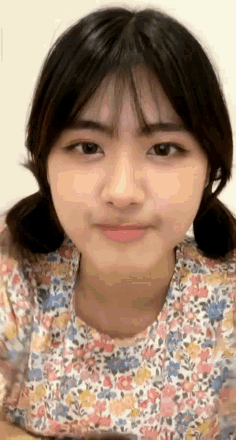 a close up of a girl 's face with a floral shirt on