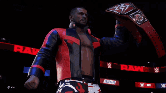 a man in a red and black leather jacket holds up a wrestling belt