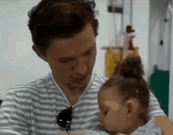 a man in a striped shirt is holding a baby girl in his arms .