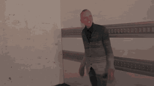 a man in a suit is standing in a room with his arms outstretched and smiling .