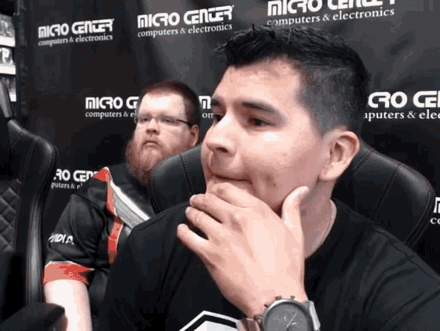 a man sitting in front of a wall that says micro center computers & electronics