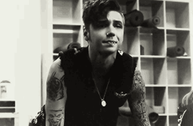 a black and white photo of a young man with tattoos