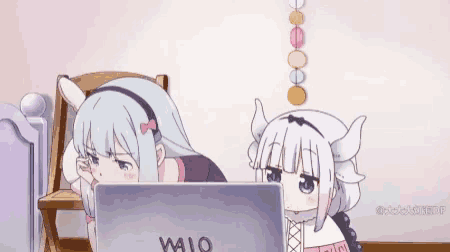 a couple of anime girls are looking at a laptop computer .