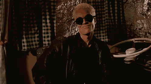 a man wearing sunglasses and a leather jacket is standing next to a car wheel .