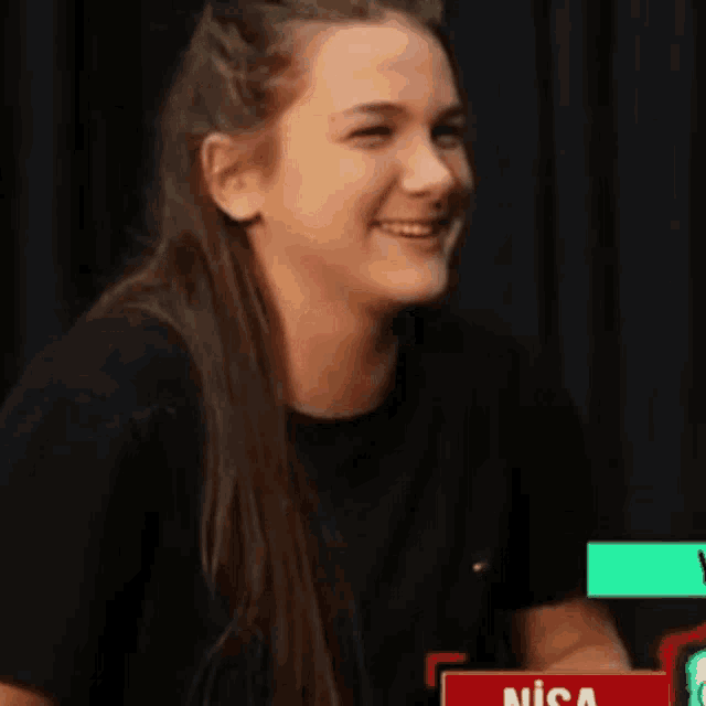 a woman in a black shirt is laughing and making a funny face with her hands .
