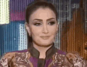 a close up of a woman wearing a purple jacket and earrings .