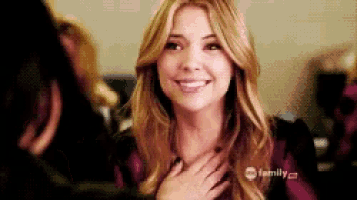 a woman with long blonde hair is smiling and holding her hands to her chest .