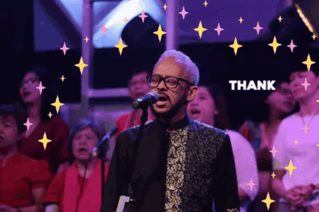 a man singing in front of a crowd with the word thank behind him